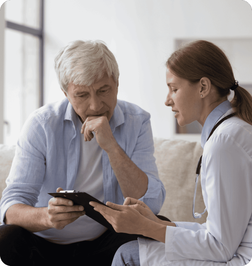 A doctor discusses information on a tablet with an older male patient who appears thoughtful; both are seated indoors.